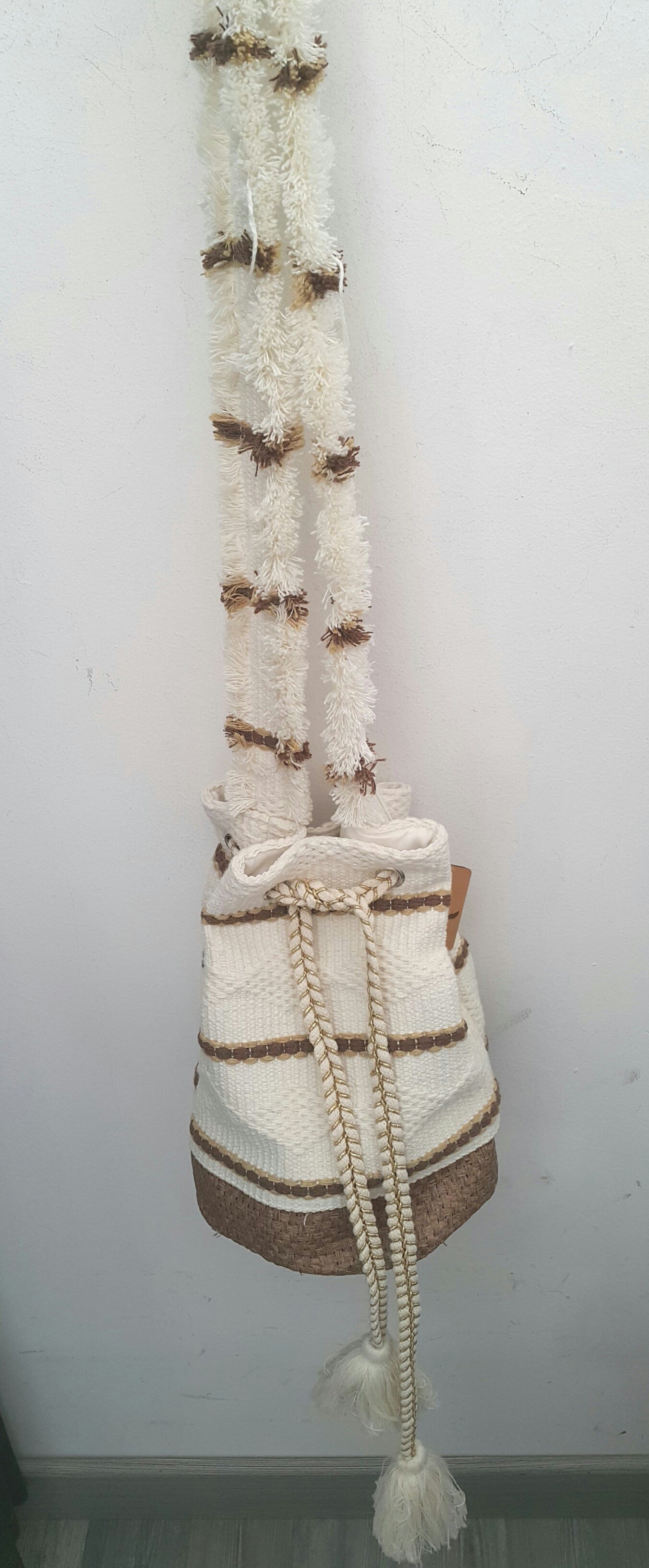 Borsa secchiello, in cotone lavorato, con rinforzo, in rafia, sul fondo. Chiude con cordoncini che terminano, sul fondo, con nappine. ModArtshop