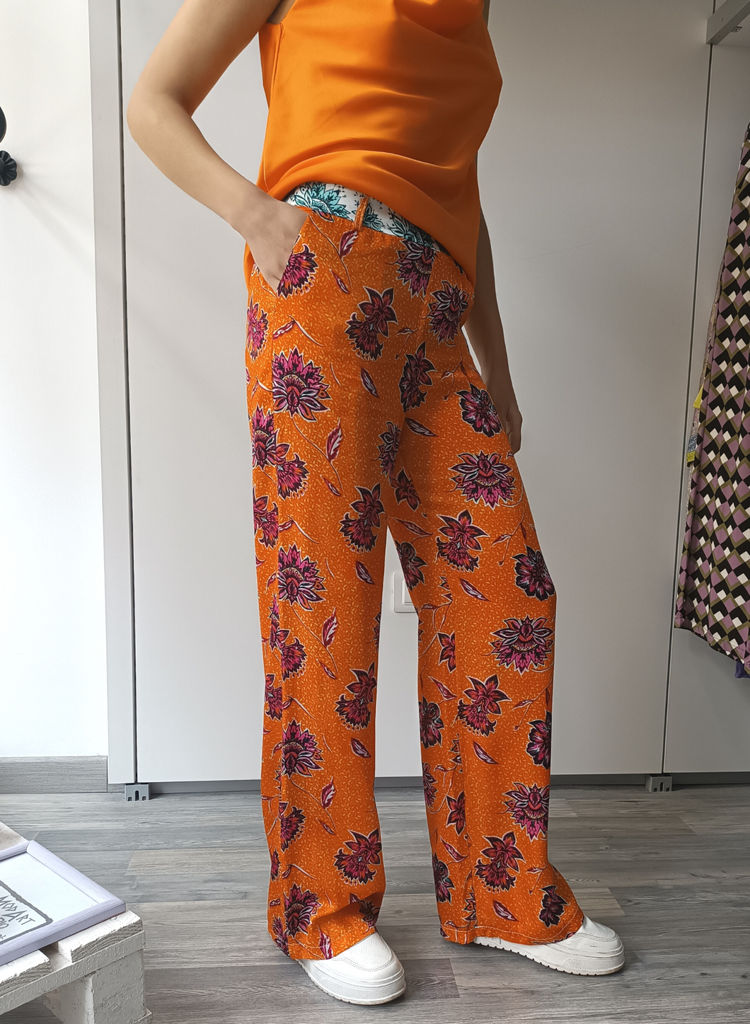 Pantaloni in fantasia floreale su fondo arancio